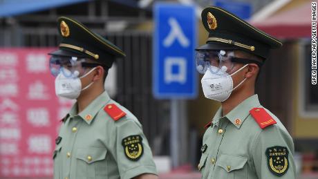 Paramilitary police officers wear protective masks and glasses as they warn at the entrance to Beijing's closed Xinfadi Market on June 13.